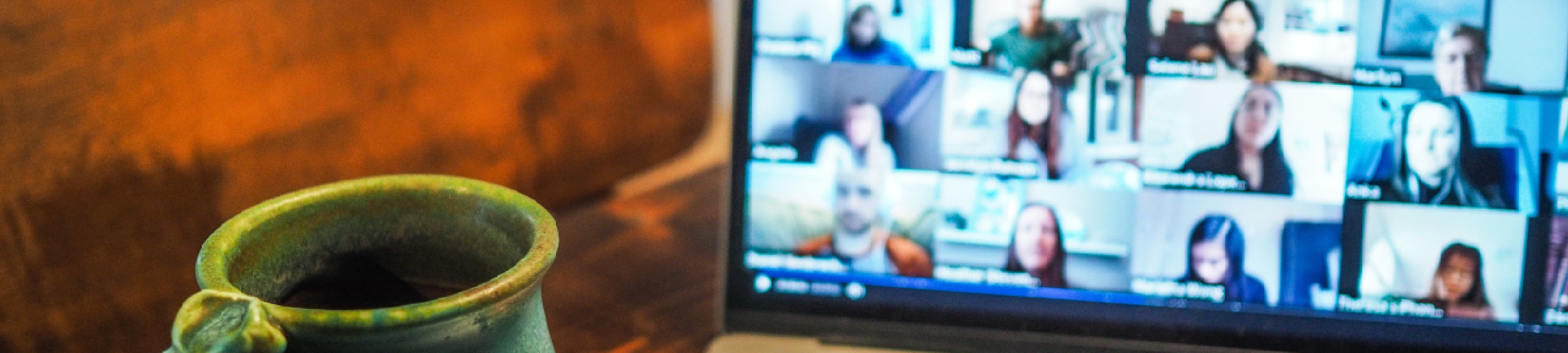 A cup of coffee is shown next to a laptop during an online meeting