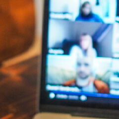 A cup of coffee is shown next to a laptop during an online meeting