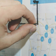 A photo of someone creating paper-based designs with cut outs and string to show a digital user experience